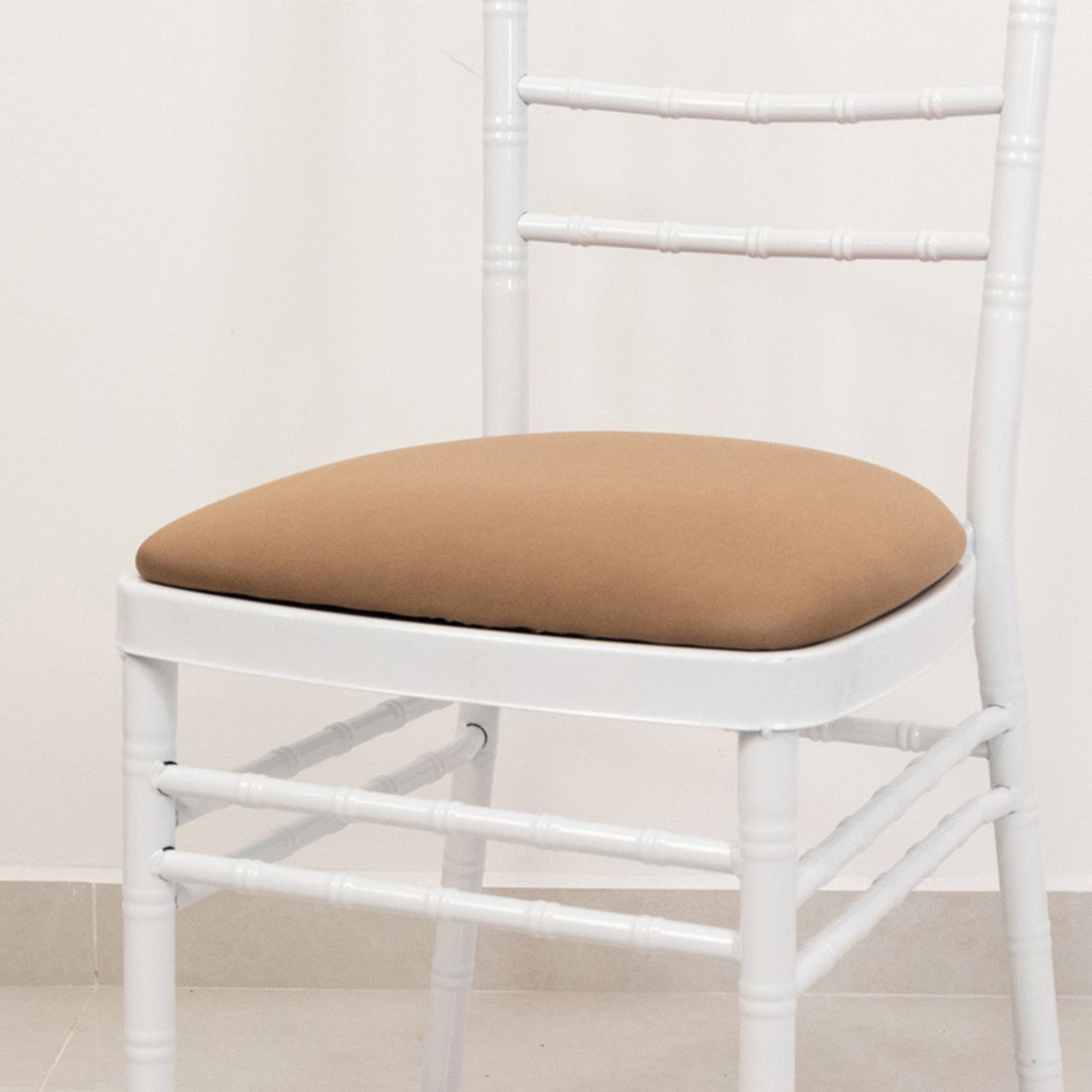White chair with a brown cushion on a plain backdrop