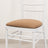 White chair with a brown cushion on a plain backdrop