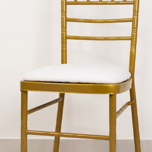 Gold chiavari chair with white cushion on a plain background