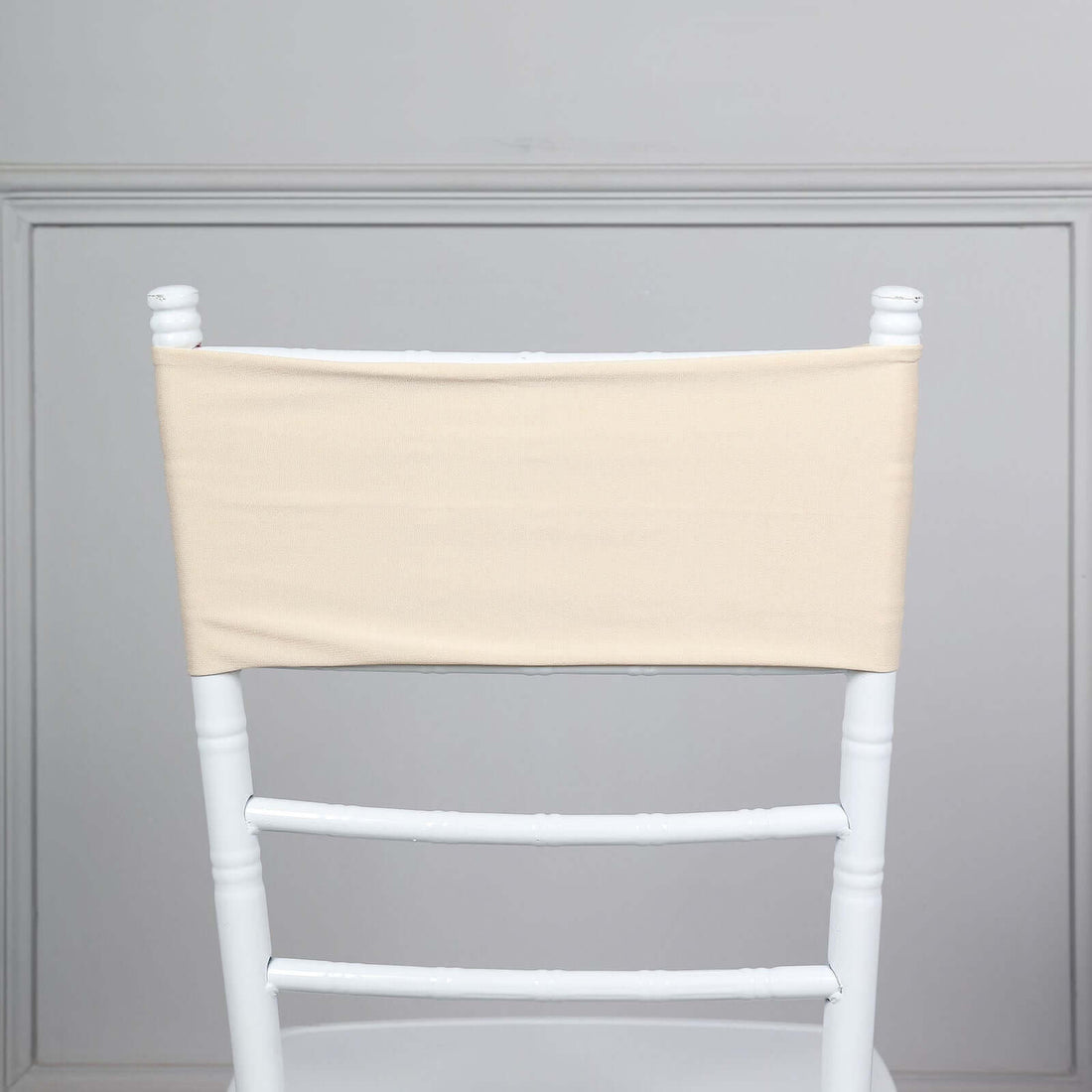 Beige chair cover on a white chiavari chair against a plain background.