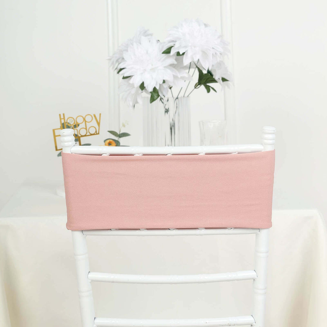 Pink chair cover on a white chair with flowers in the background.
