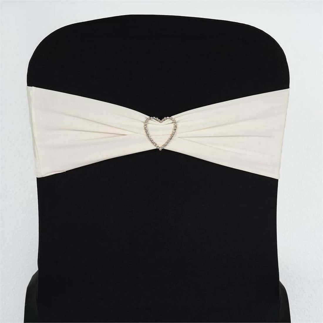 Ivory satin chair sash with heart-shaped embellishment on black chair