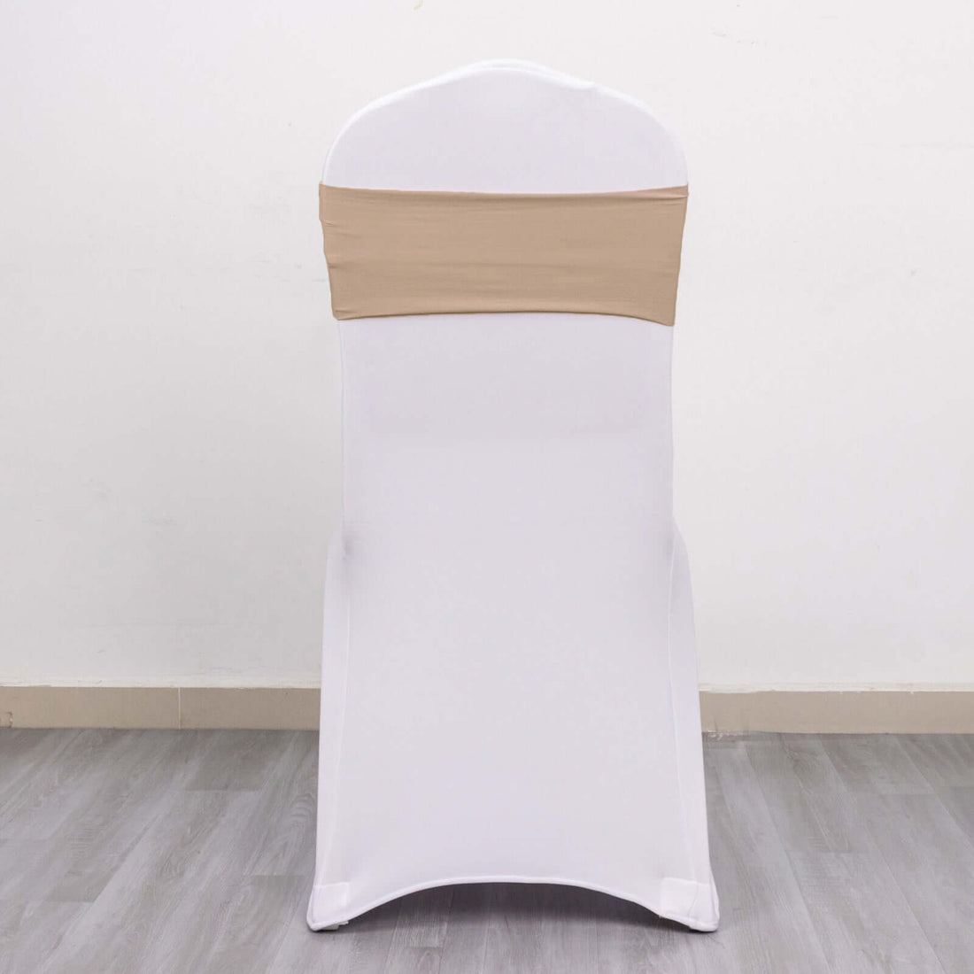 White chair cover with beige sash on a plain backdrop