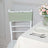 White chiavari chair with a mint green cover next to a dining table and floral centerpiece.