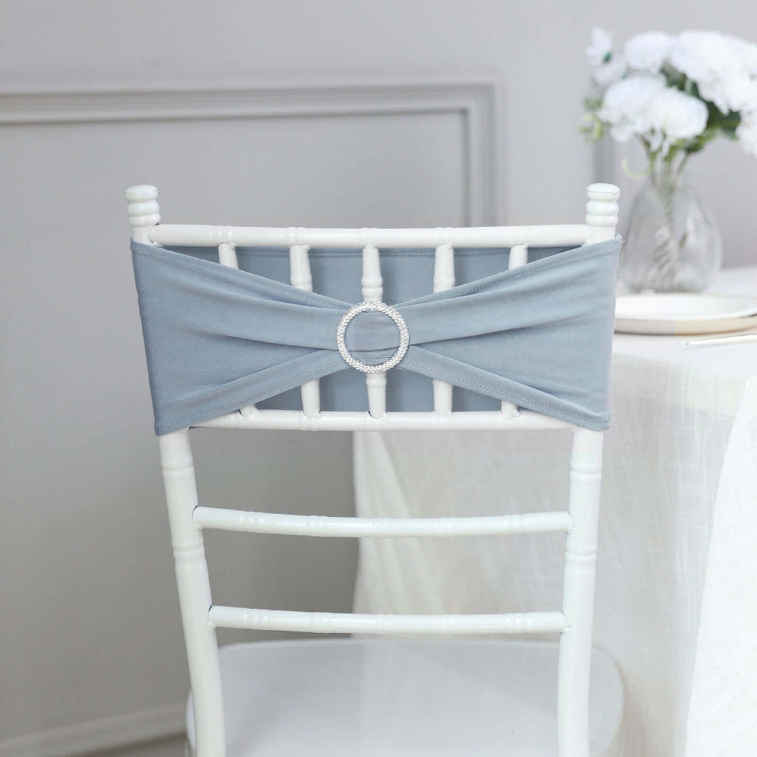 Grey chair sash with rhinestone ring on a white chiavari chair.