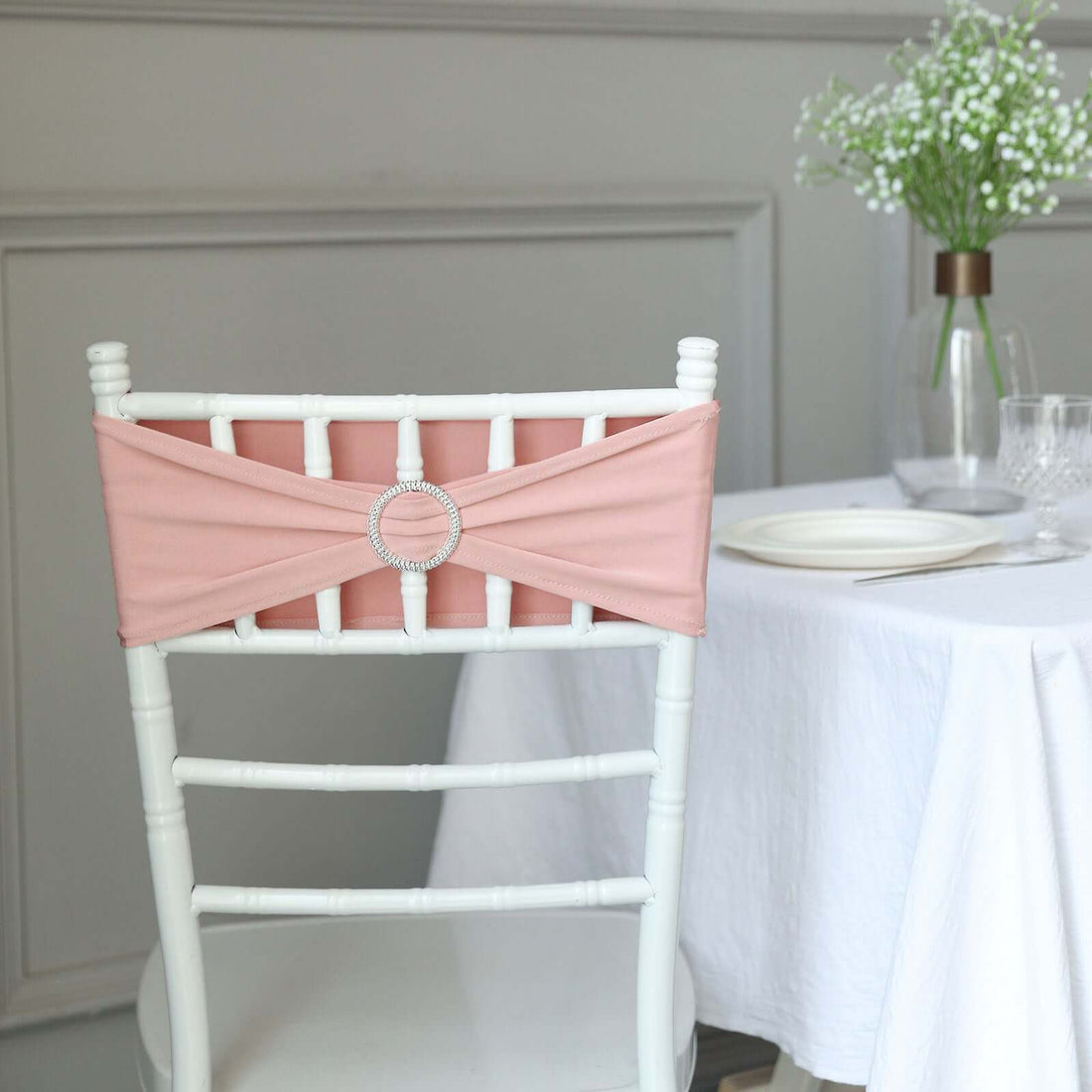 Pink chair sash with a decorative buckle on a white Chiavari chair.