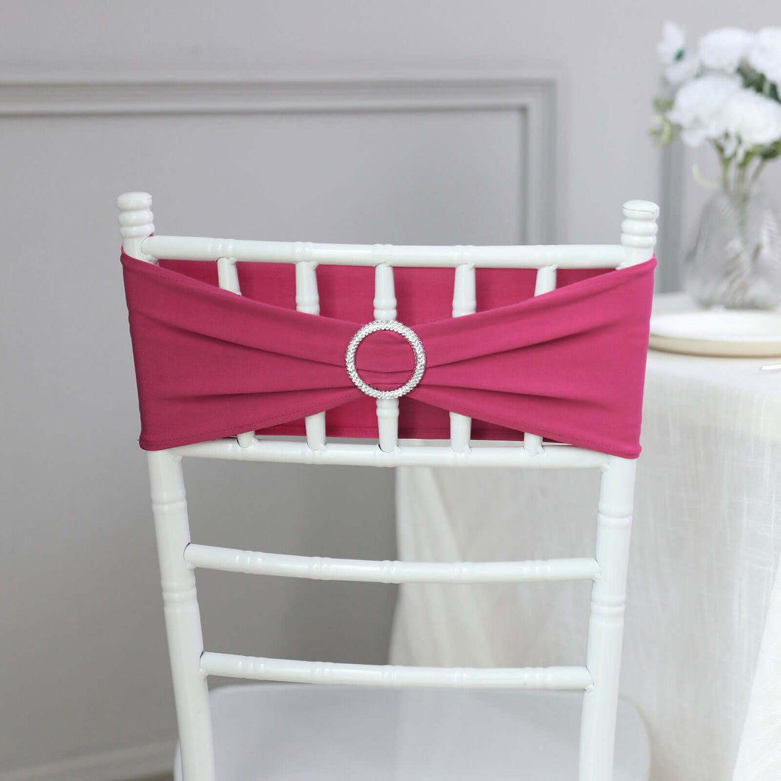 Pink chair sash with rhinestone embellishment on a white chiavari chair.