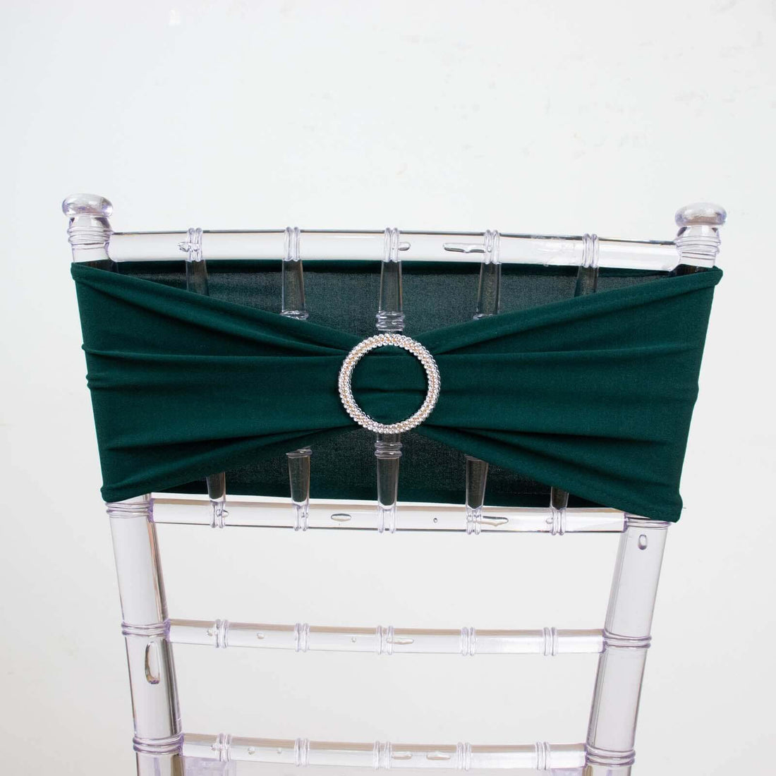 Green chair sash with rhinestone buckle on a clear chiavari chair.