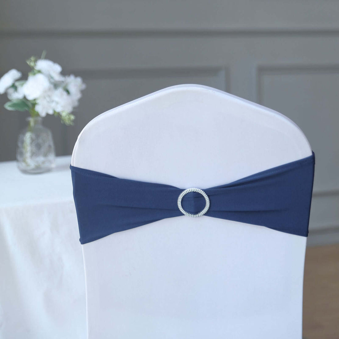 Navy chair cover with decorative buckle for elegant event decor.