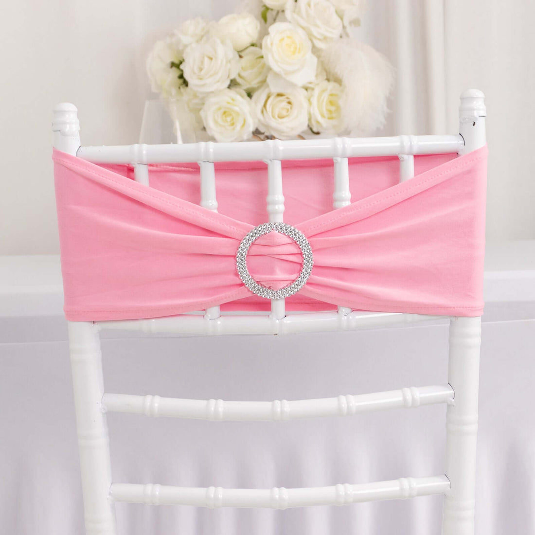 Pink chair sash with rhinestone buckle, elegantly draped on a white chiavari chair.