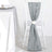 Gray table runner draped elegantly on a white chair with a decorative flower.