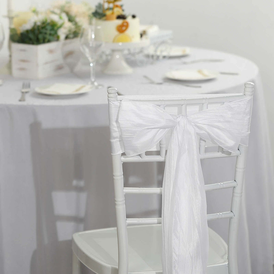 White chair with elegant ribbon bow at a decorated dining table.