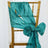 Teal satin chair sash tied in a bow on a gold chair. 
