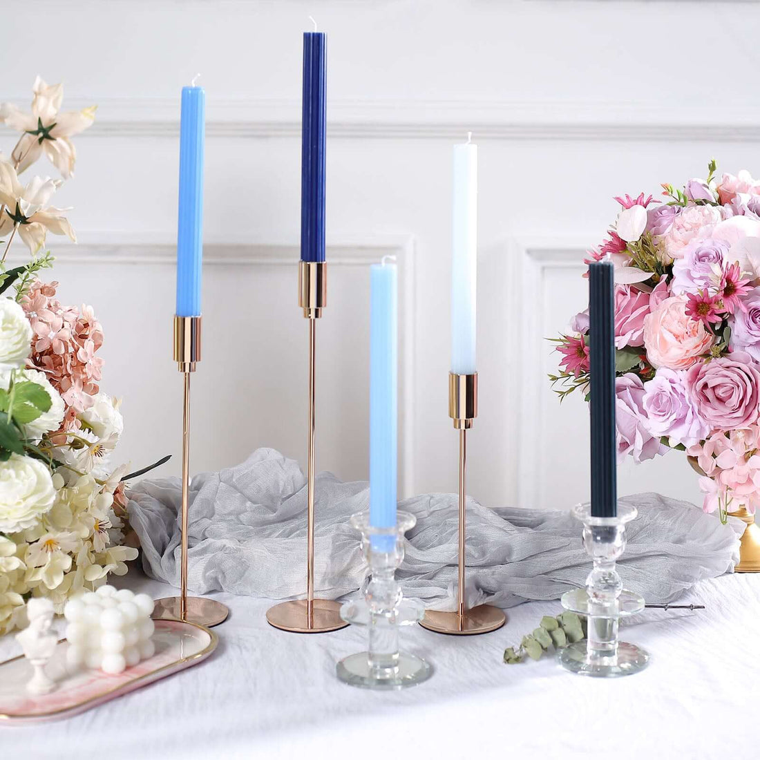 Elegant candle holders with blue and white candles, surrounded by floral decor.