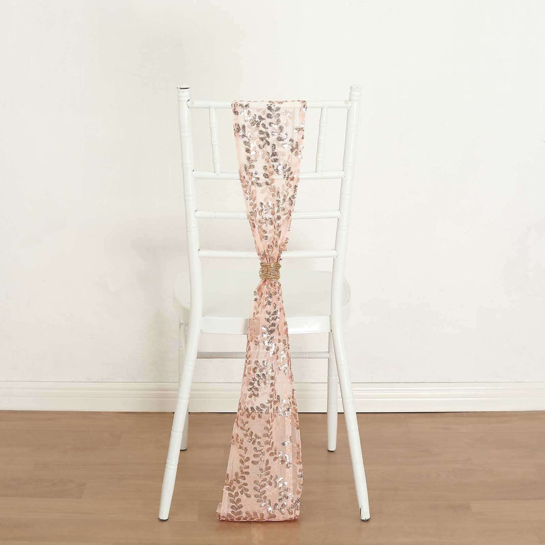Rose gold sequin chair sash tied on a white chair.