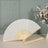 Elegant white folding fan with wooden handle displayed next to a vase of flowers.