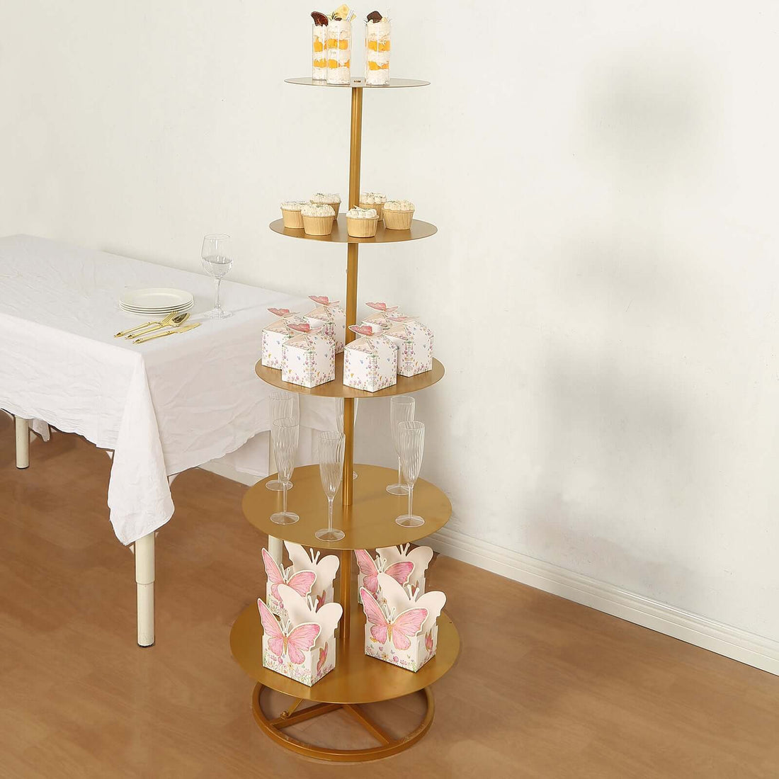 Gold dessert stand with cupcakes, pastries, and decorative boxes.