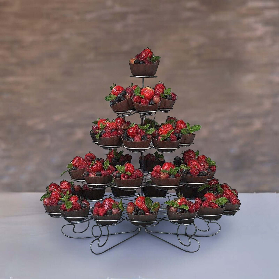 Berry display in a decorative tiered stand with fresh strawberries and mint leaves.