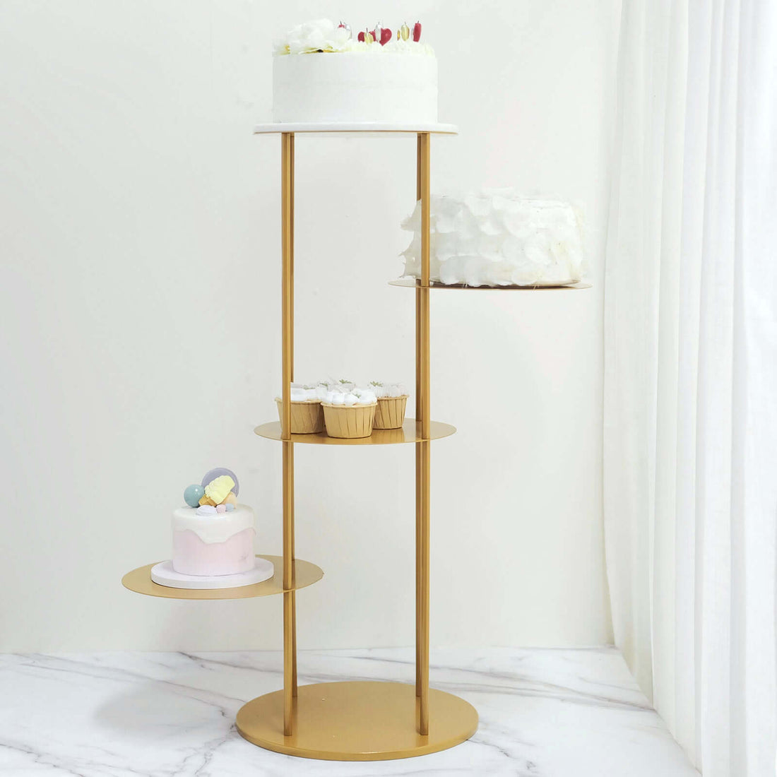 Gold dessert stand with cakes and cupcakes on a marble surface.