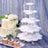White tiered dessert stand with pastries and a cake on a glittery background.