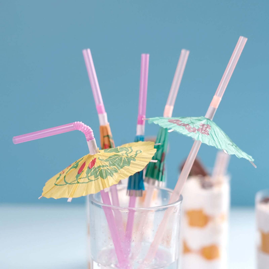 Colorful cocktail umbrellas with straws in a glass.