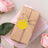 Gift-wrapped package with twine and yellow tag, surrounded by pink roses.