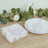 Floral paper napkins on a wooden table with greenery and a plate.