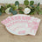 Decorative pink floral napkins arranged on a plate with greenery background.