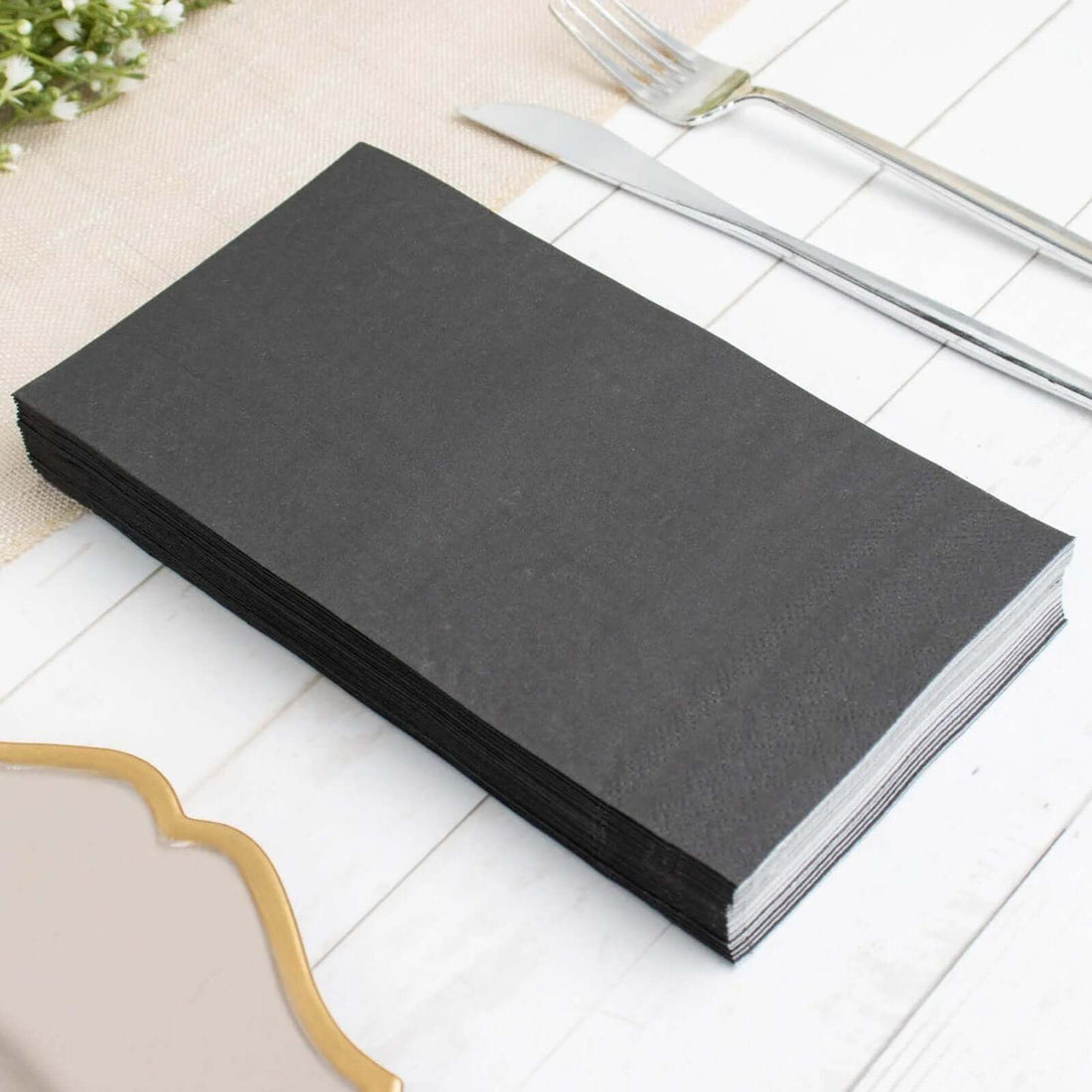 Black disposable napkins stacked on a table.