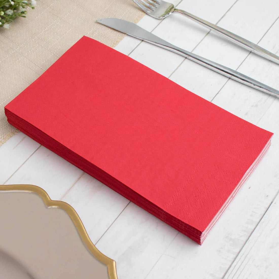Stack of red paper napkins on a white wooden table.
