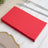 Stack of red paper napkins on a white wooden table.