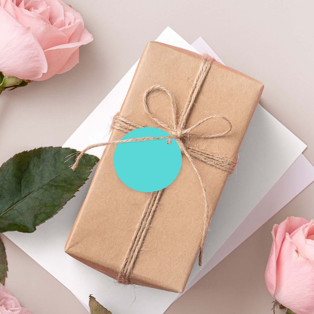Gift wrapped package with a teal tag, surrounded by pink roses.