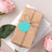 Gift wrapped package with a teal tag, surrounded by pink roses.