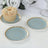 Elegant blue and gold dessert plates with a cupcake on a textured table setting.