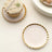 Pink and gold decorative plate with a cupcake on a textured surface.