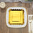 Gold and white square plate with scalloped edges on a wooden table setting.