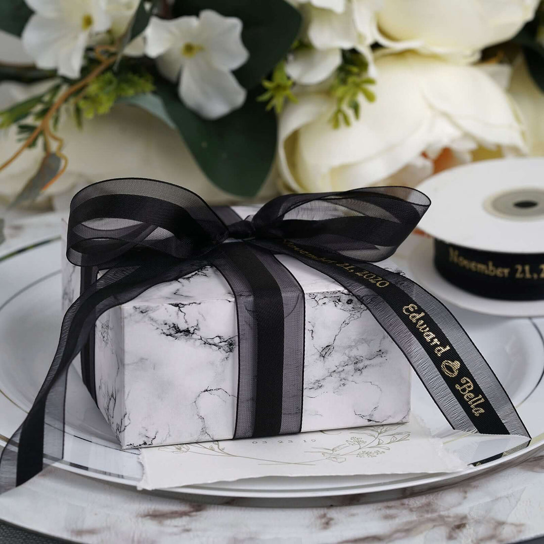 Marble gift box with black ribbon on a decorative table setting.