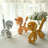 Colorful balloon animals in silver, peach, and gold displayed on a table.