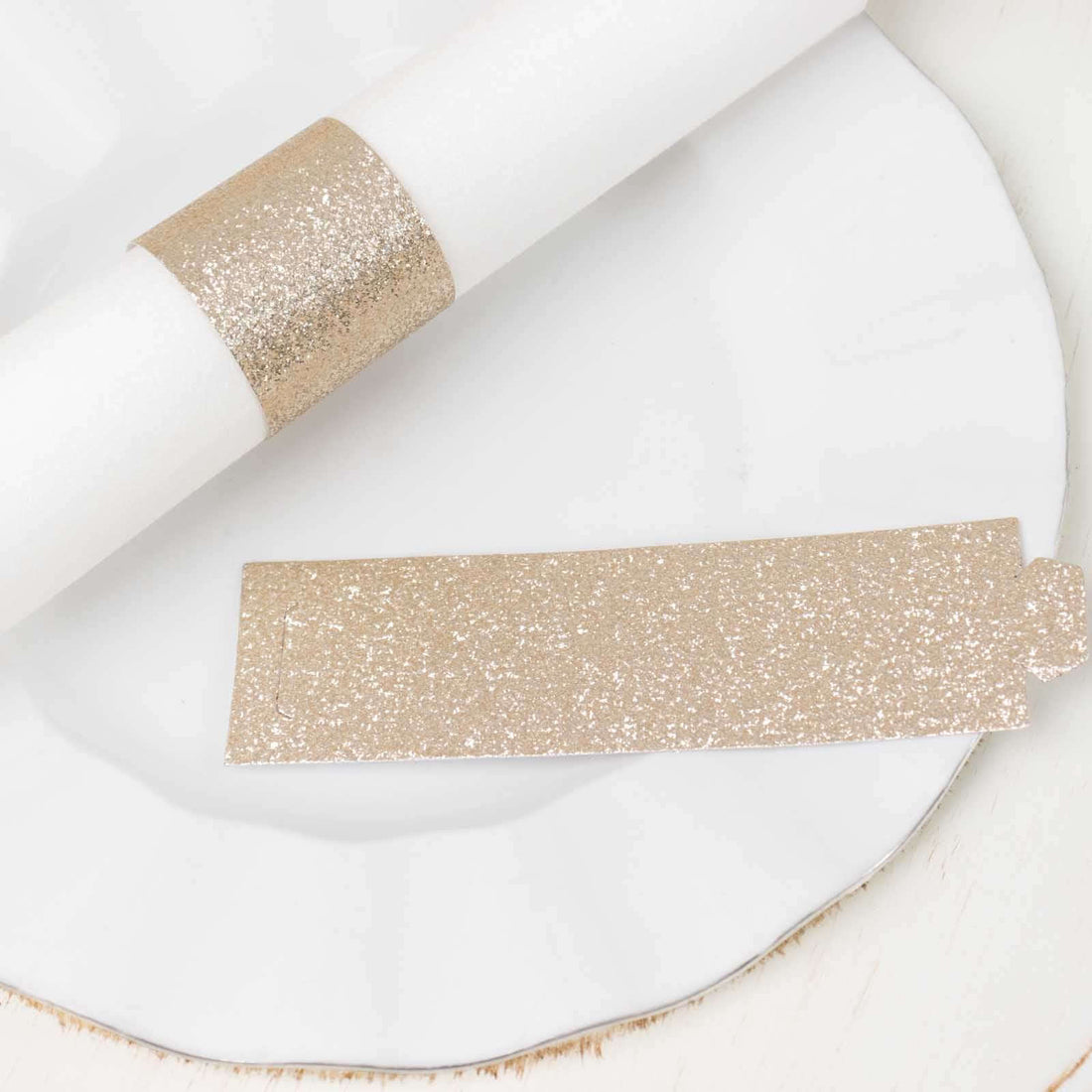 Gold glitter napkin ring and tag on a white plate.