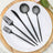 Black plastic cutlery set on a white plate with wooden board background.