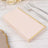 Blush pink napkins with gold trim stacked on a rustic wooden table.