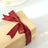 Elegant gift box with a burgundy ribbon on a light background.