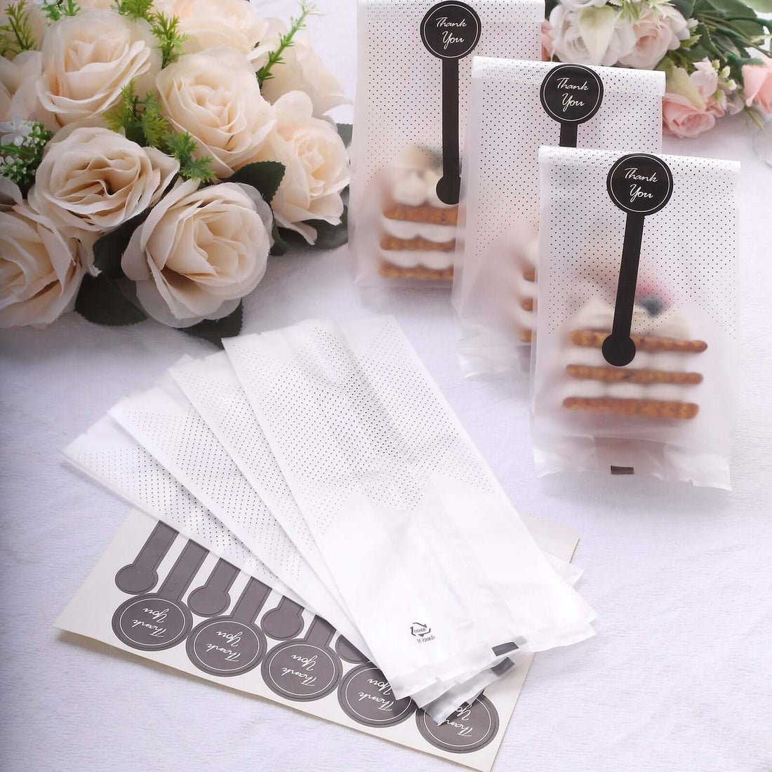 Cookie bags with "Thank You" stickers and decorative floral arrangement.