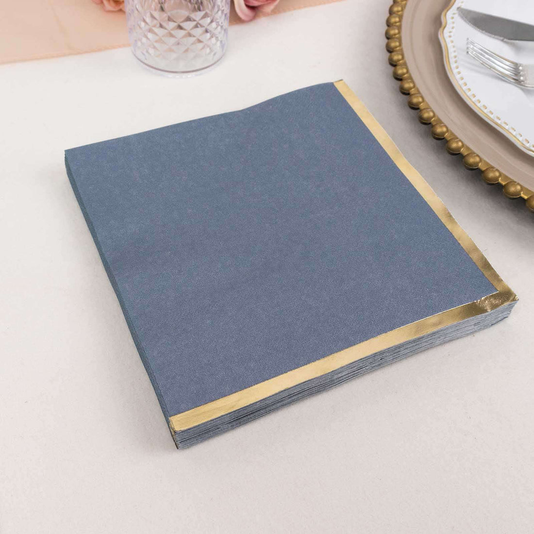 Gray napkins with gold trim stacked on a table.
