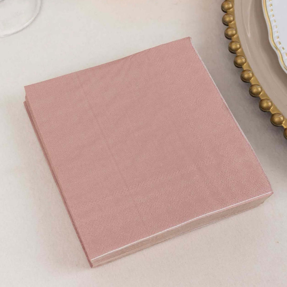 Rose pink napkin stacked on a table setting.