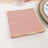 Pink napkins with gold trim stacked neatly on a table.