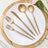 Gold cutlery set on a white plate with a wooden serving board.