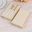 Elegant gold-trimmed cream napkins with fork and knife on a wooden table.