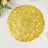 Gold decorative lace doily on a white surface.