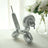 Silver balloon dog sculpture with floral arrangement in background.
